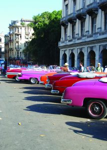 A rainbow of antique cars used as taxis line up in Havana near the capitol building.